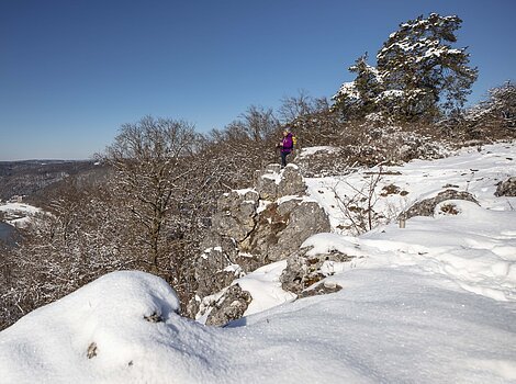 Wanderer auf dem schneebedecktem Teufelsfelsen bei Riedenburg