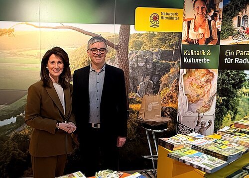 Messestand Naturpark Altmühltal mit Ministerin Kaniber im Februar 2026 Zwei Personen stehen vor einem Messestand mit Broschüren und einem Banner des Naturparks Altmühltal.