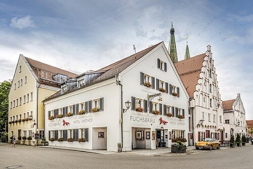 Hotel Fuchsbräu in Beilngries Das Hotel mit 3 Häusern an einer Straßenecke ist zu sehen. Im Hintergrund noch die beiden Türme der Stadtpfarrkirche.